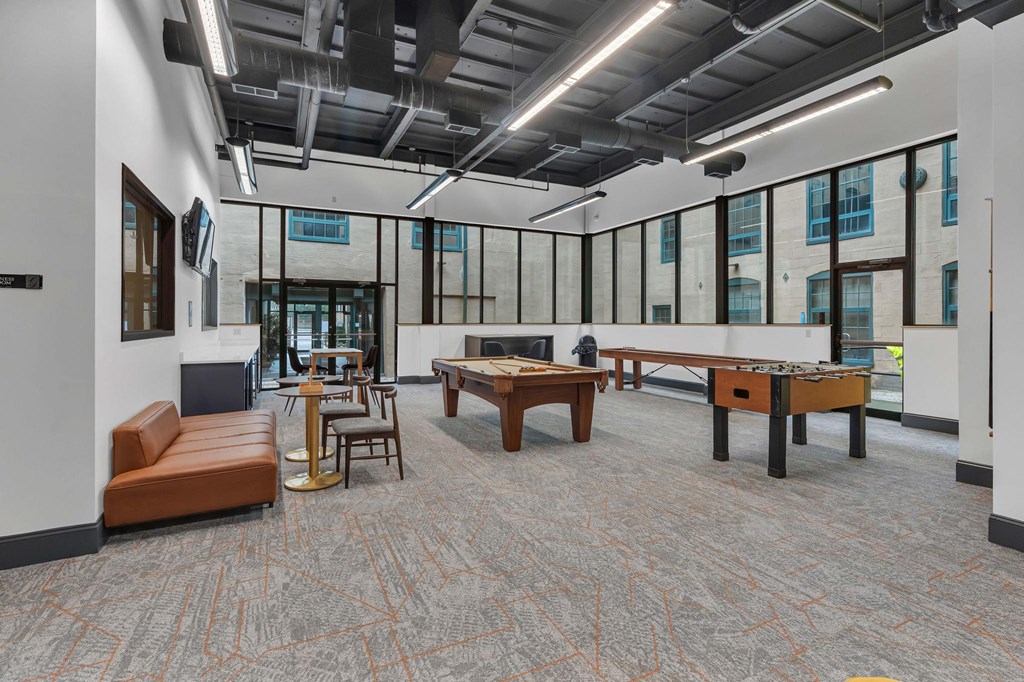 A room with a carpeted floor and a variety of seating options including a couch, chairs, and a table.