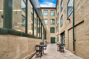 A narrow alley with tables and chairs on either side.