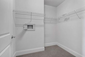 A white room with a door and a small white box on the wall.