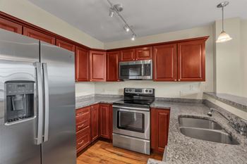 A kitchen with a stainless steel refrigerator and wooden cabinets.