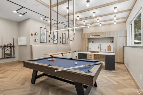 A pool table is in the middle of a room with a wooden floor.