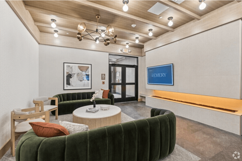 A modern waiting room with a green velvet sofa and a coffee table.