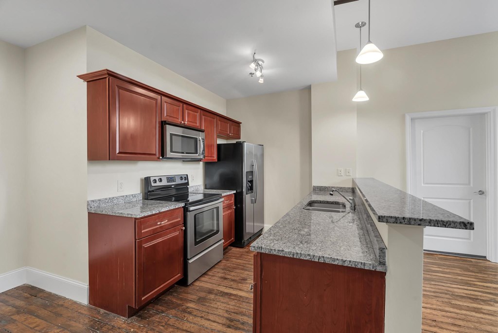 A kitchen with a granite countertop and wooden cabinets.