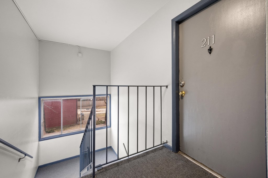 an empty room with a door to a balcony and a stairwell