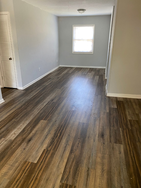 an empty living room with hardwood floors and a window