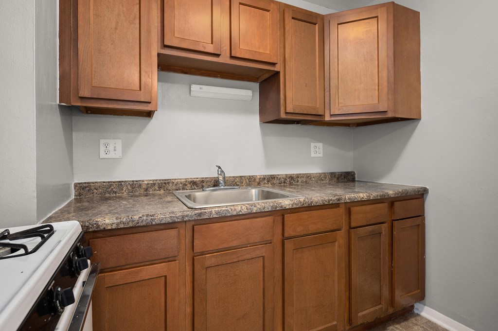 an empty kitchen with wooden cabinets and granite counter tops