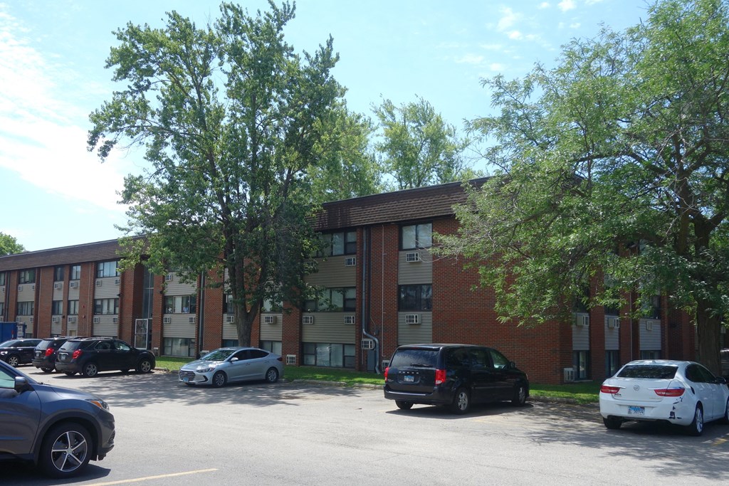 an apartment building with cars parked in a parking lot