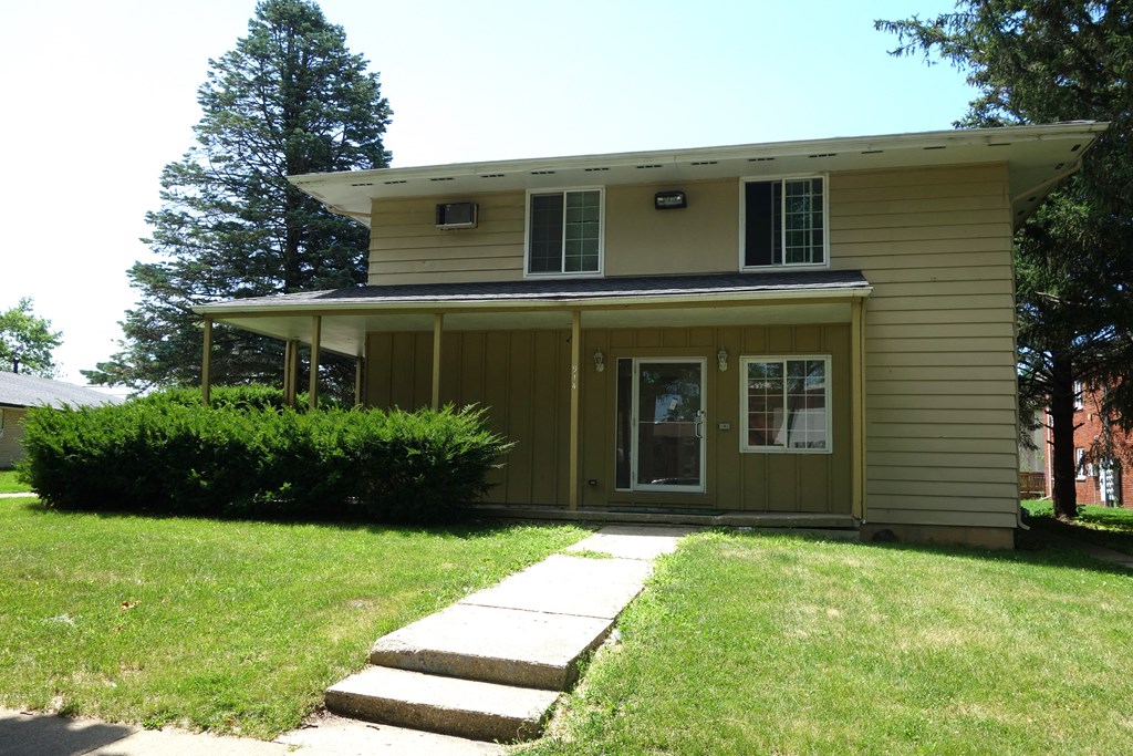 a yellow house with a sidewalk in front of it