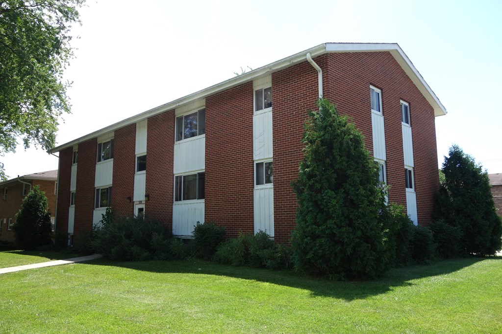 a building with a green lawn and trees in front of it