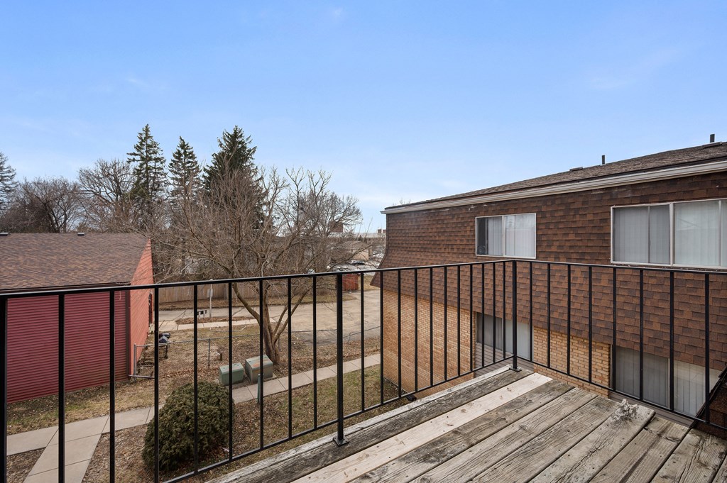a balcony with a wooden deck and a brick building