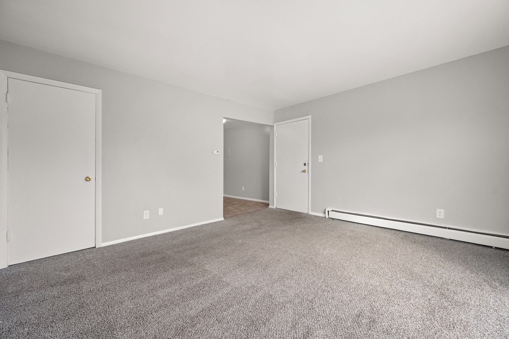 an empty living room with carpet and white walls