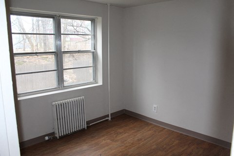 an empty room with a radiator and a large window