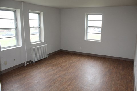 A room with wood floors and two windows.