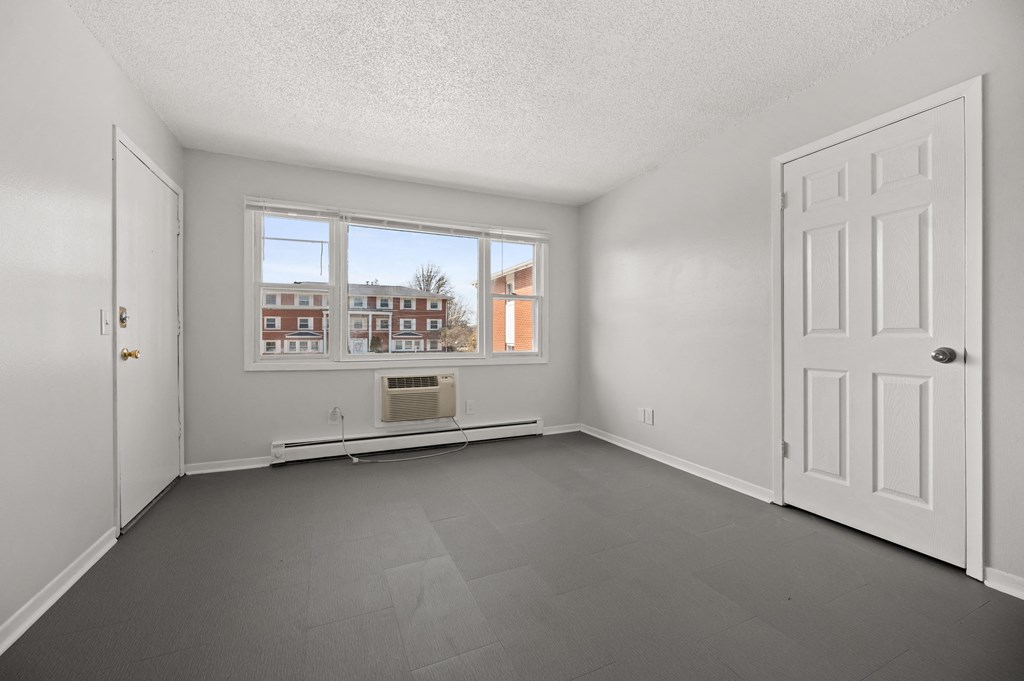 an empty living room with white walls and a window