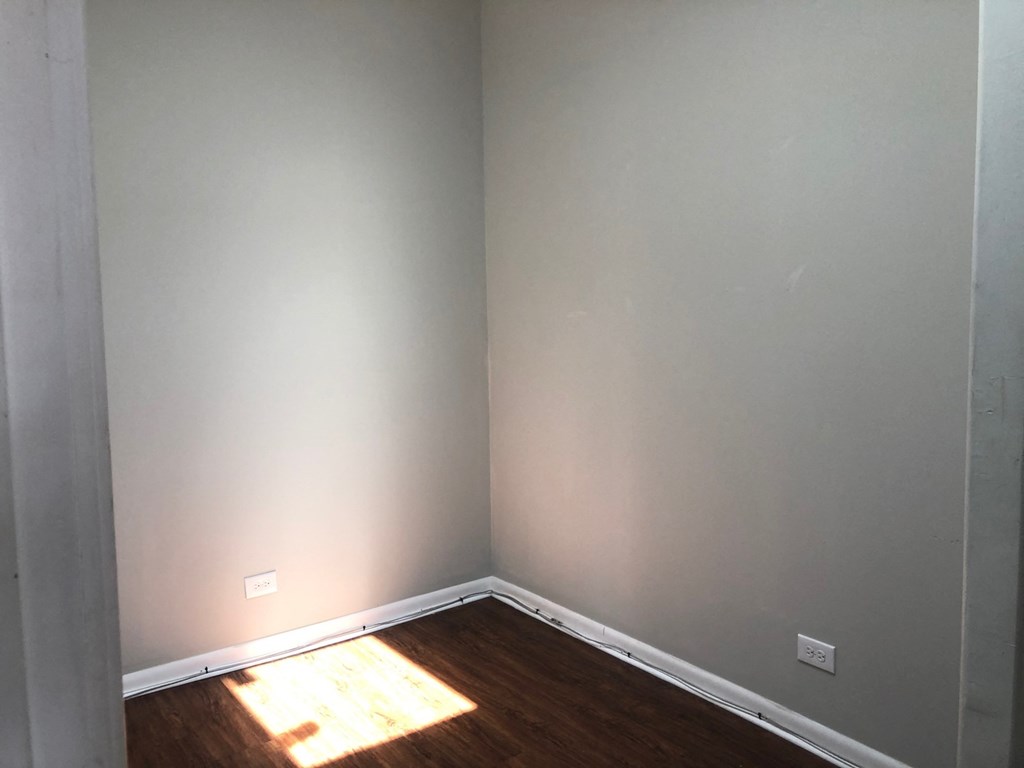 the corner of a room with wood flooring and gray walls