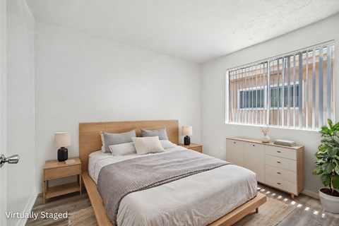 A bedroom with a bed, nightstands, and a plant.