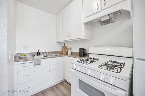 A white kitchen with a stove top oven and a sink.
