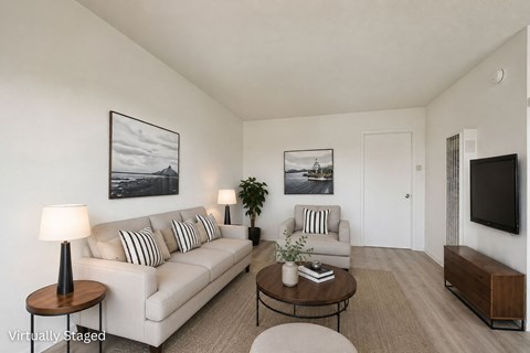 A living room with a white couch, a coffee table, and a television.