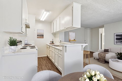 A white kitchen with a table and chairs in the foreground.
