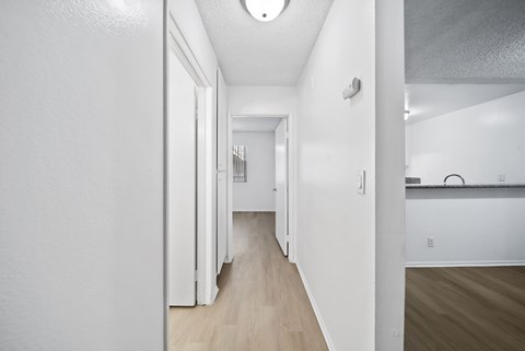 A long hallway with white walls and wood floors.
