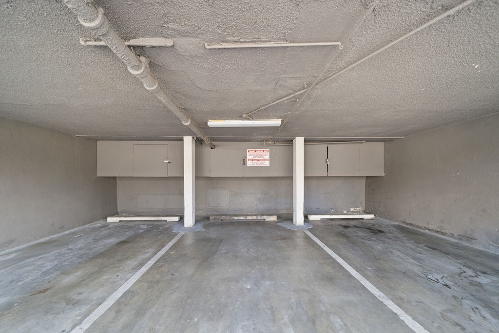 A spacious, unfinished room with concrete floors and walls, and exposed pipes on the ceiling.