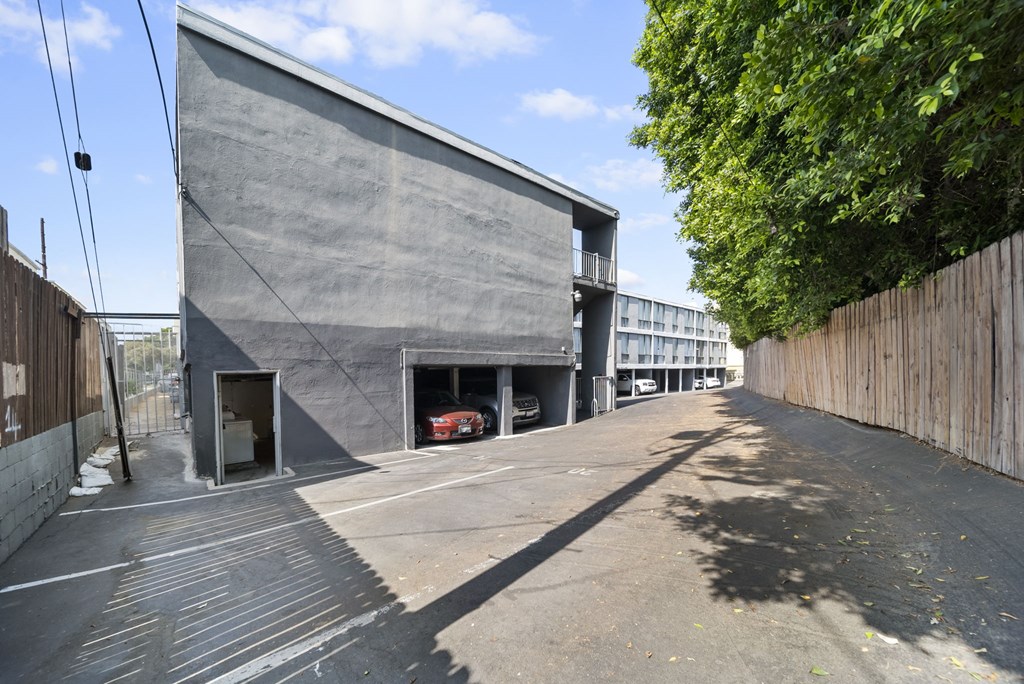 A grey building with a red car in the garage.