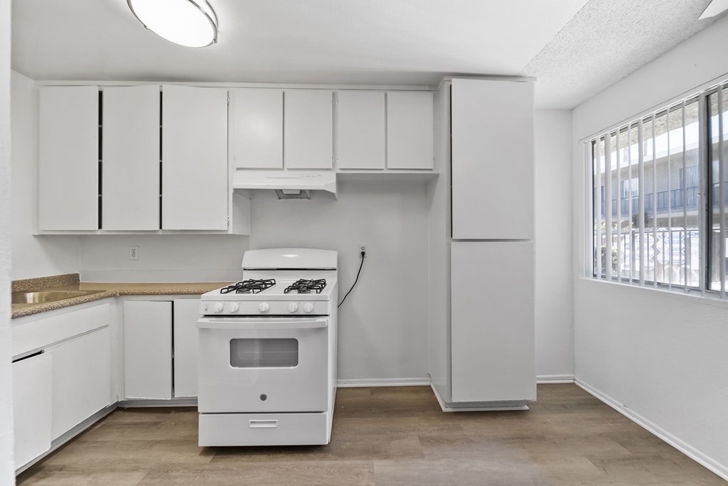 A white kitchen with a stove and cabinets.