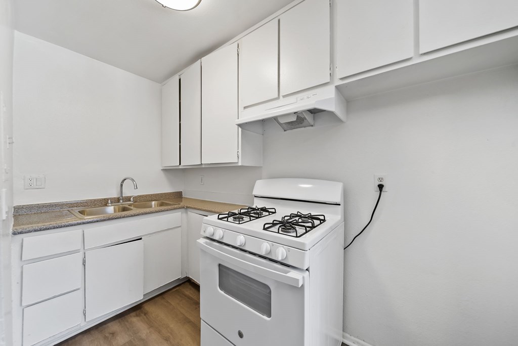 A white kitchen with a stove and cabinets.