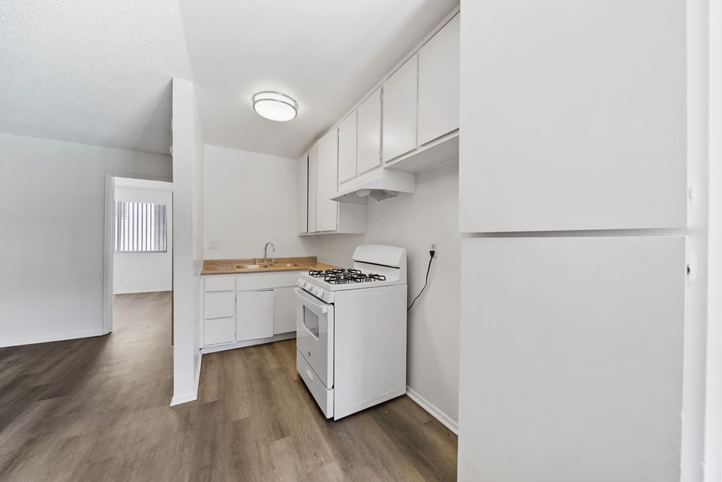 A white kitchen with a stove and a window.