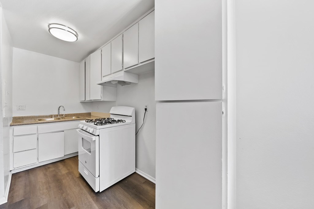 A white kitchen with a stove and sink.