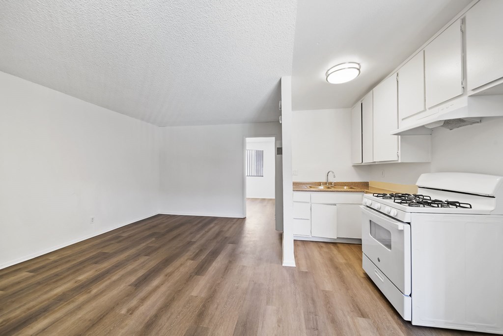 A kitchen with white appliances and wooden floors.