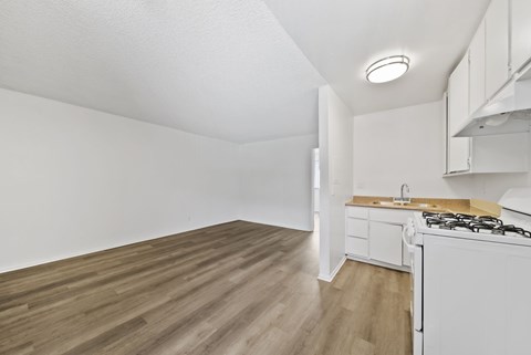 A kitchen with a white stove and wooden floors.