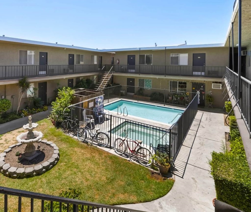 A pool surrounded by a fence and a bicycle.
