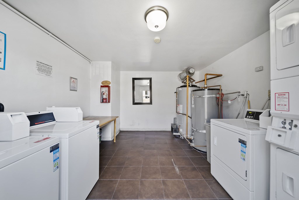 A laundry room with washing machines and a bench.