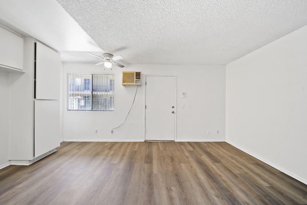 A room with a ceiling fan and a window with blinds.