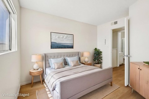 A bedroom with a large bed and a painting on the wall.