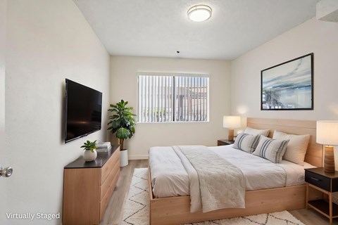 A large bedroom with a window letting in natural light