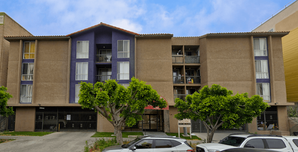 A large apartment complex with a parking lot in front.