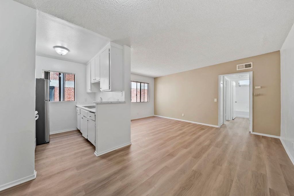 A kitchen with white cabinets and a refrigerator.