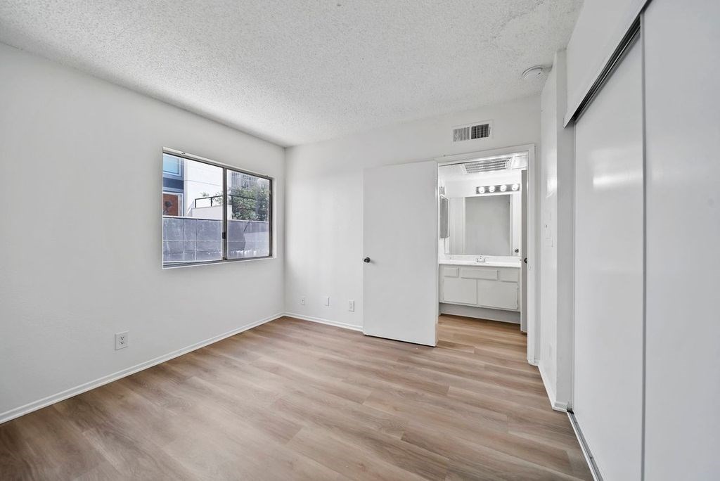 A white room with a wooden floor and a window.