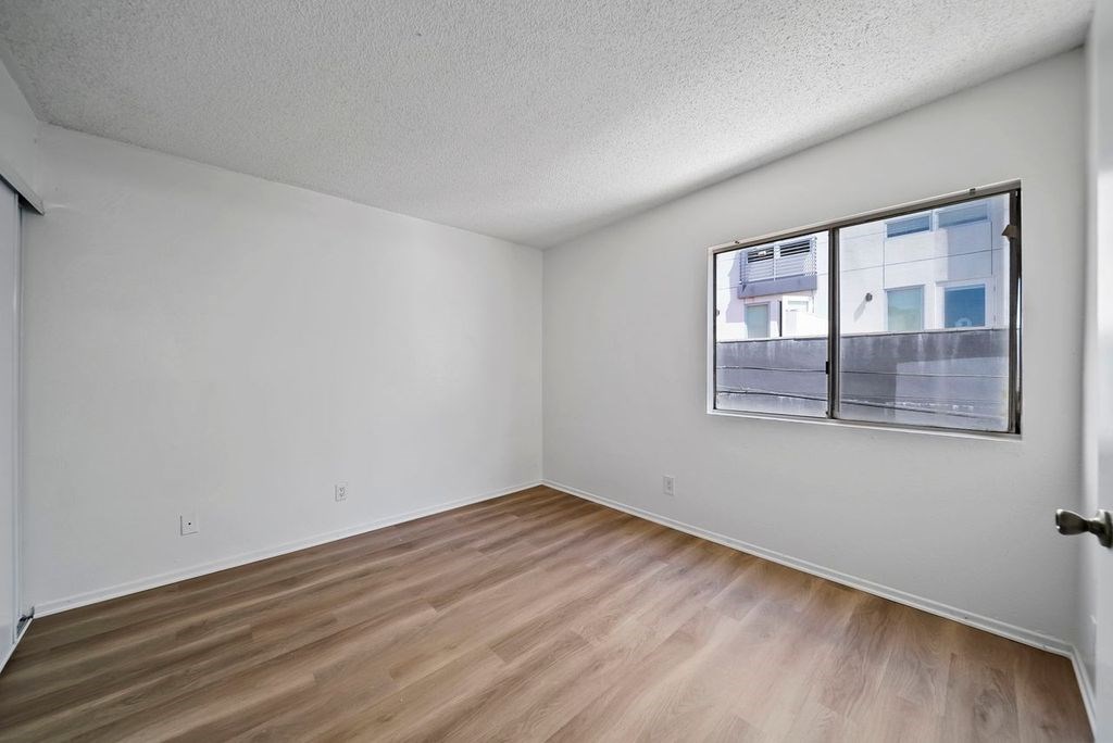 Empty room with a window and wooden flooring.