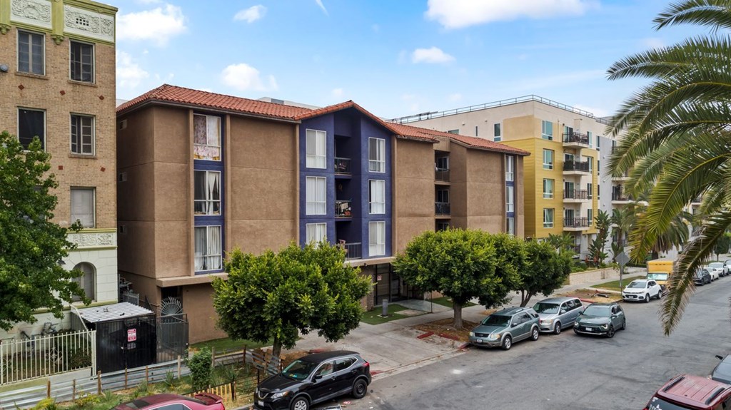 A view of a street with cars and apartment buildings.
