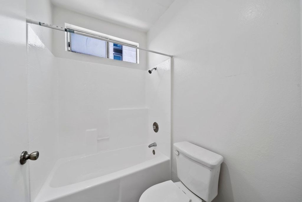 A white toilet sits next to a white bathtub in a small bathroom.