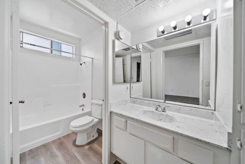 A white bathroom with a toilet, sink, and mirror.