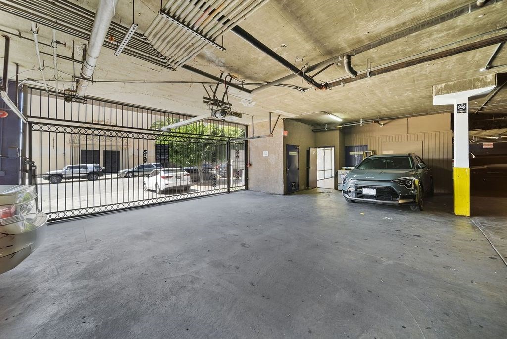 A car is parked in a garage with a yellow pole to the right.