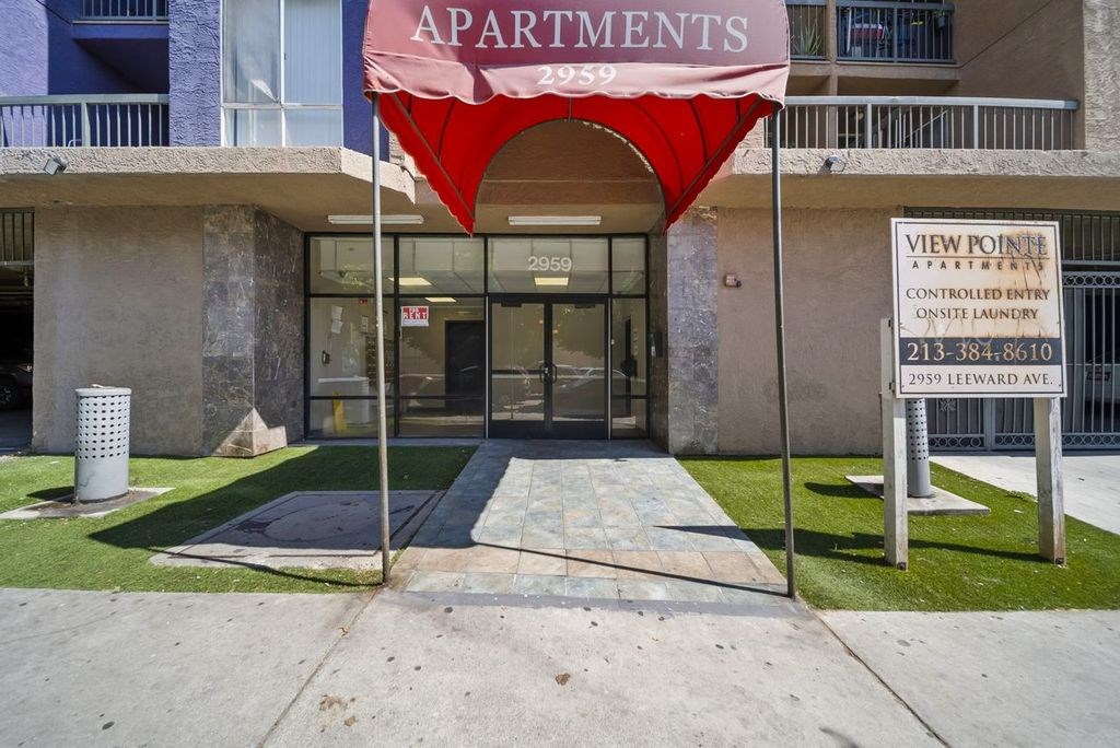 The entrance to apartment building 2959 with a red umbrella.