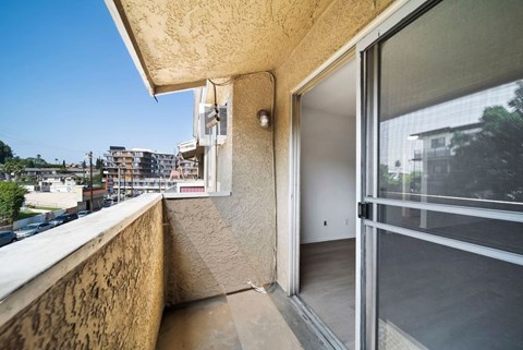 A balcony with a glass door leading to a room with a view of the city.