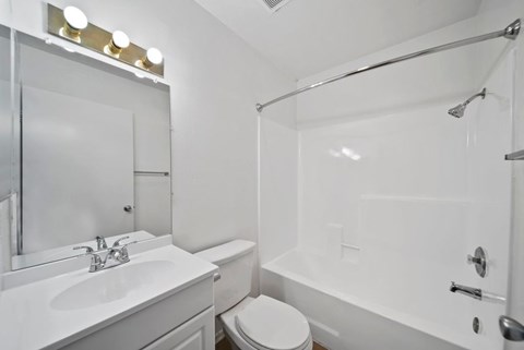 A white bathroom with a sink, toilet, and bathtub.
