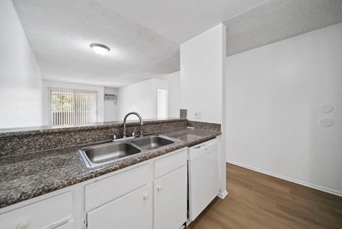 A kitchen with white cabinets and a granite countertop.