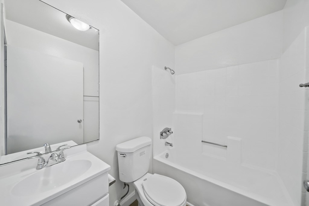 A white bathroom with a toilet, sink, and bathtub.